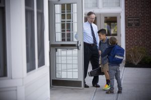 Head of school opening door for students