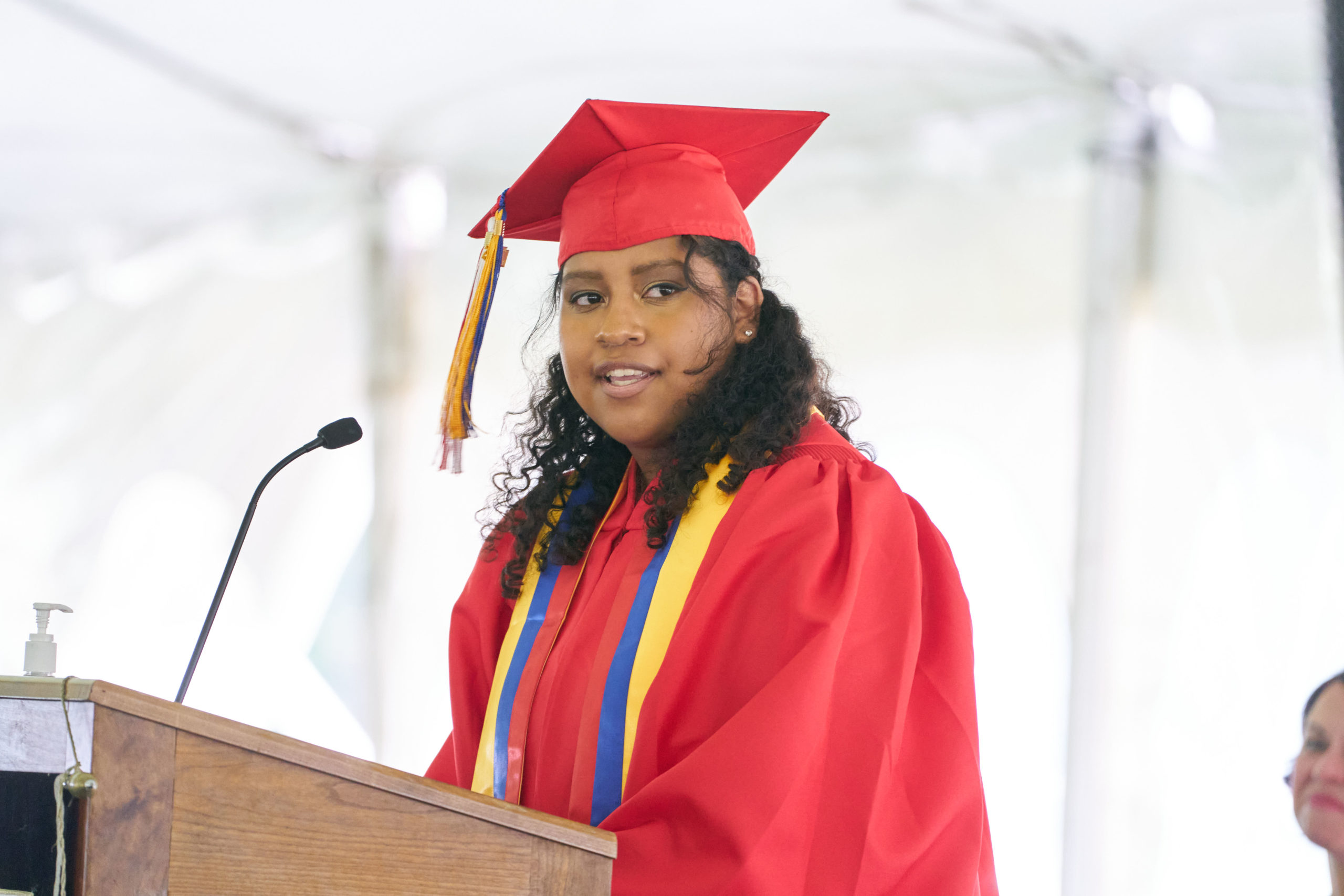 Student at podium in graduation gown and cap